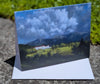 Painting of the Omni Mount Washington Hotel with the Presidential Range beyond and big clouds overhead.