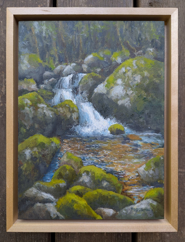 Painting of a waterfall surrounded by rocks and greenery in a wooden frame.