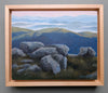 Painting of a landscape with rocks and mountains in a wooden frame.