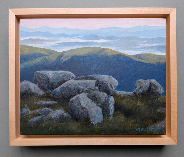 Painting of a landscape with rocks and mountains in a wooden frame.