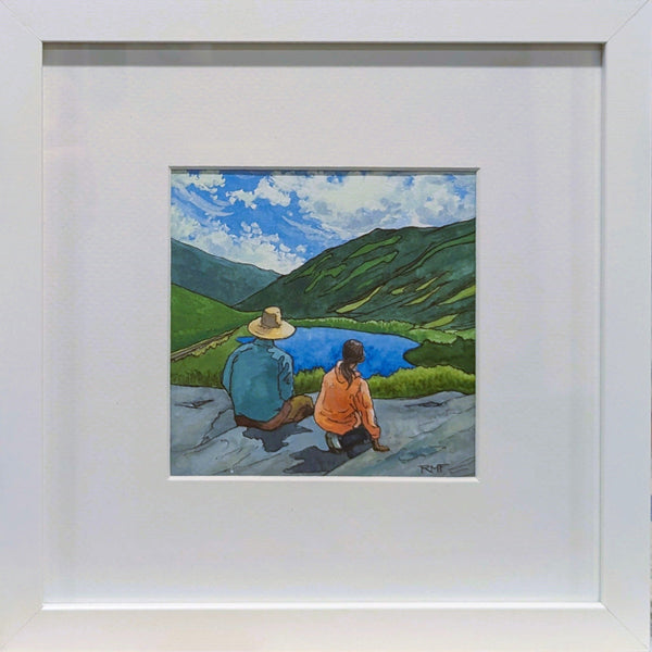 A framed watercolor painting featuring a landscape with mountains, a lake, and two figures seated next to each other, appreciating the view.