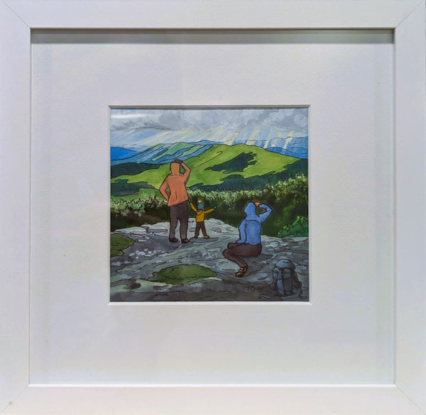 A framed watercolor and ink painting depicting two adults and a child on a mountaintop, looking off at the view.