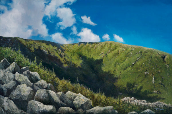 Scenic landscape with green hills, blue sky, and clouds.