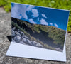 Scenic card with a mountain landscape and blue sky on a stone surface