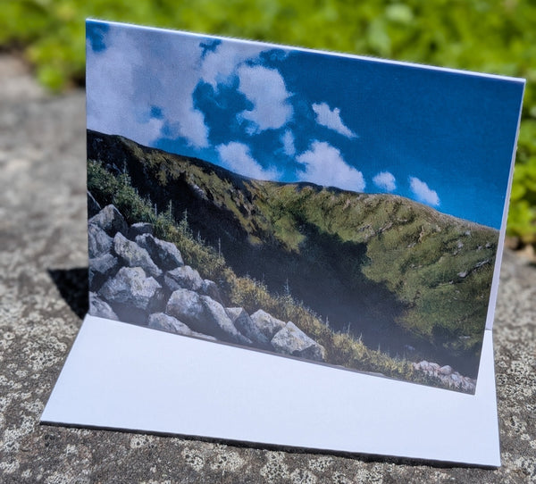 Scenic card with a mountain landscape and blue sky on a stone surface