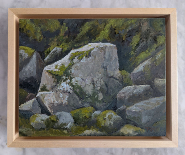 Framed ainting of rocks with green moss in a wooden frame on a textured gray background