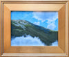 Framed artwork of a mountain landscape with blue sky and clouds.