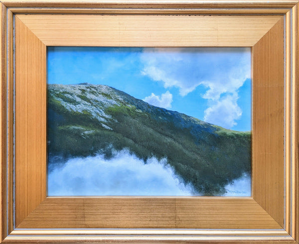 Framed artwork of a mountain landscape with blue sky and clouds.