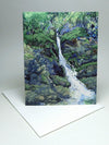 A small blank greeting card featuring a painting of a white brook flowing through a green forest.